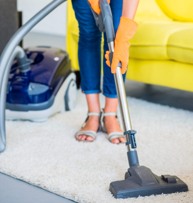 A woman is vacuuming the floor in her living room.